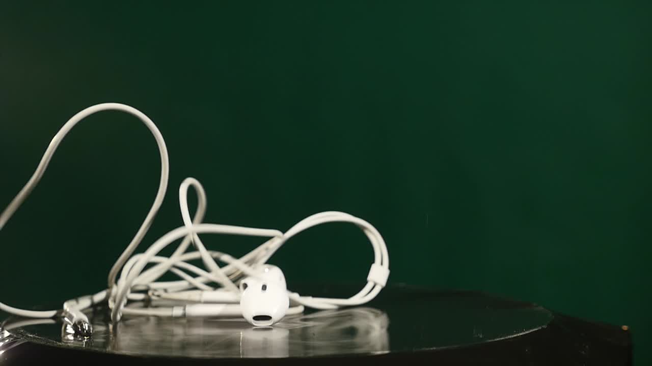 прыгающие наушники на движущемся субвуфере на зеленом фоне