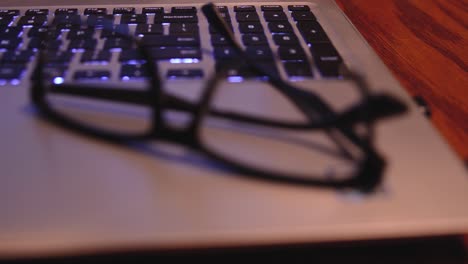 rack focus shot of a pair of eyeglasses resting on top of a laptop computer