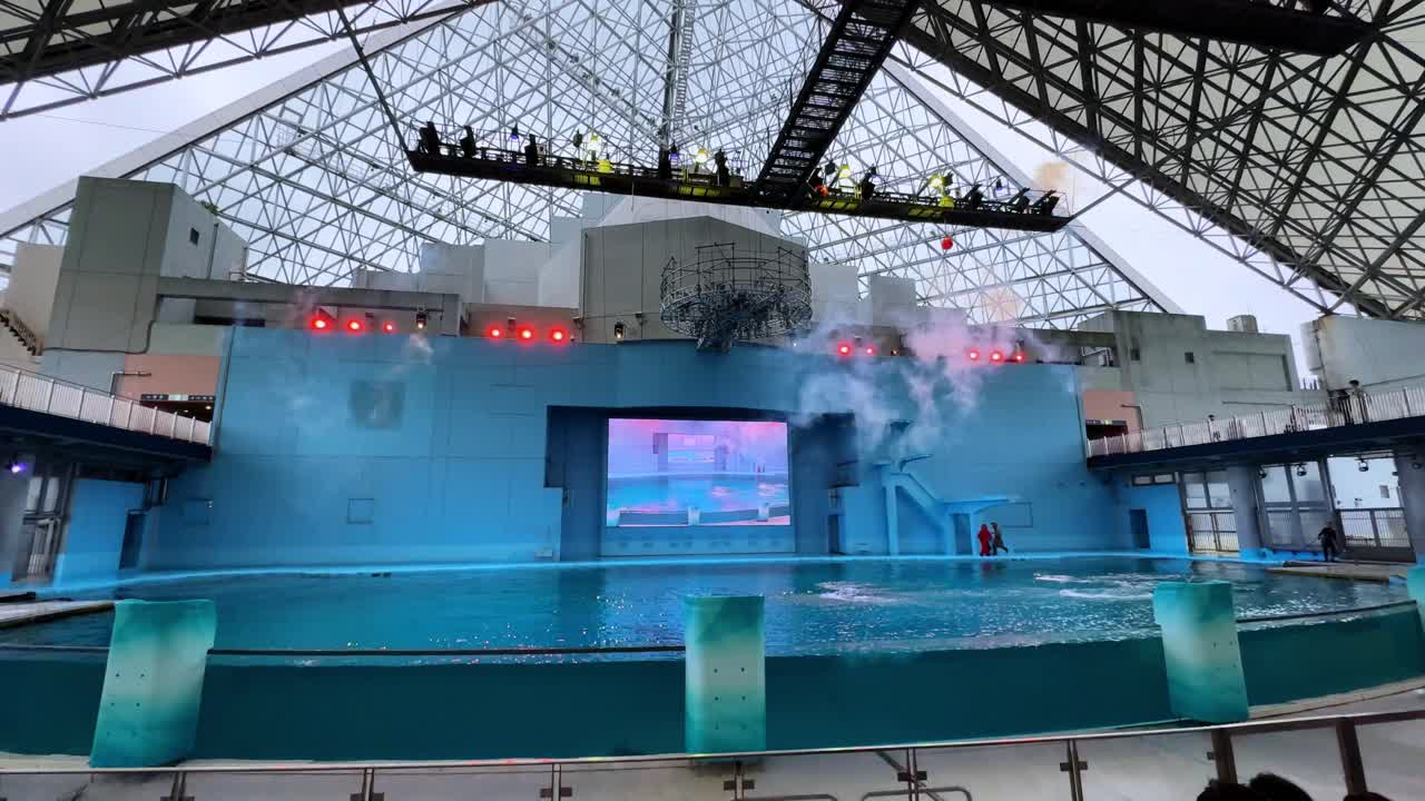 An indoor aquarium show with smoke effects and bright lights inside a modern glass dome