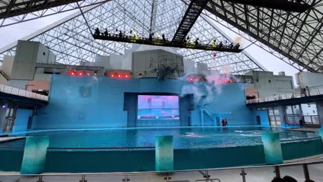 an indoor aquarium show with smoke effects and bright lights inside a modern glass dome