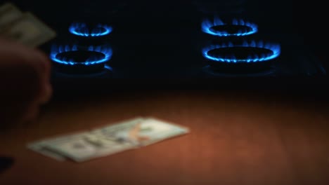 a man counts one hundred dollar bills against the background of a lit gas stove with gas. rec focus