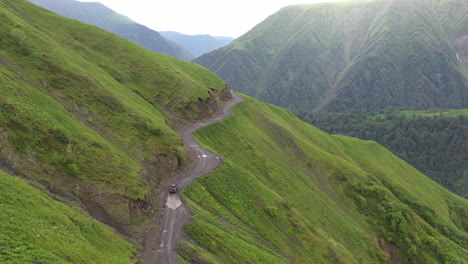 Disparo-Cinematográfico-De-Un-Dron-Descendente-De-Un-Vehículo-Conduciendo-Por-La-Carretera-A-Tusheti,-En-El-Cáucaso,-Una-De-Las-Carreteras-Más-Peligrosas-Del-Mundo