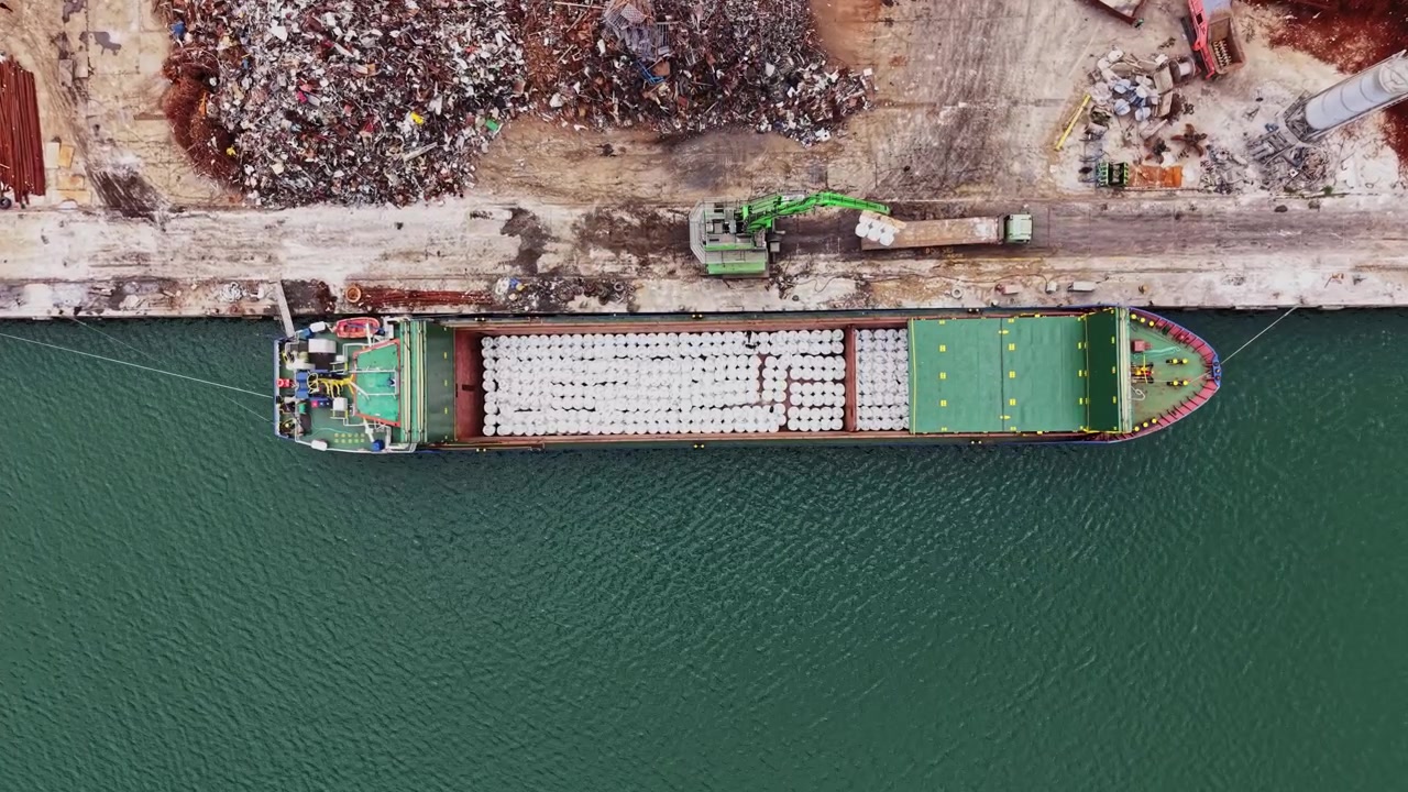 Buque de carga descarga materiales en el puerto cerca de un desguace por la tarde