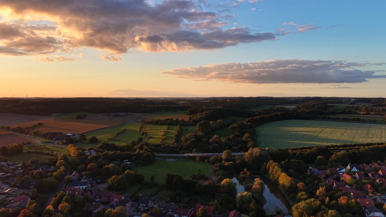 Vibrant peaceful sunset time over small American town in late summer. Aerial wide shot. Houses and homes with Traffic on rural highway and roundabout. Colored sky in the evening