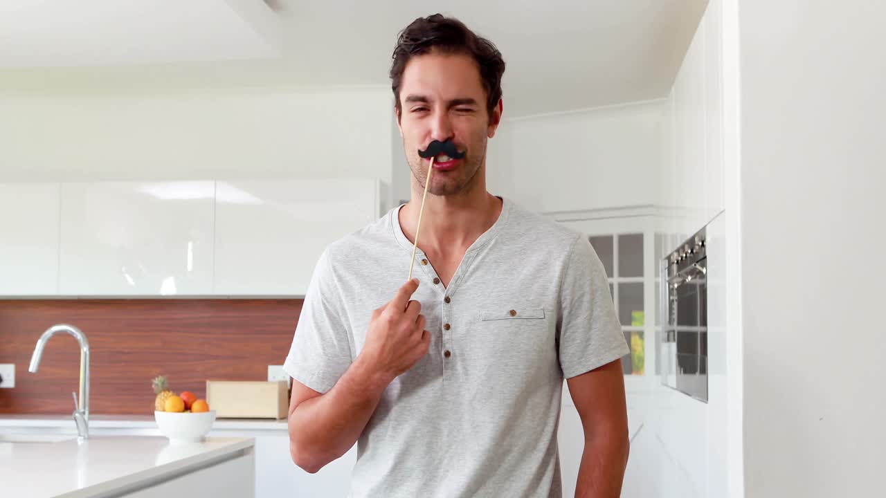 Hombre apuesto con bigotes falsos haciendo muecas