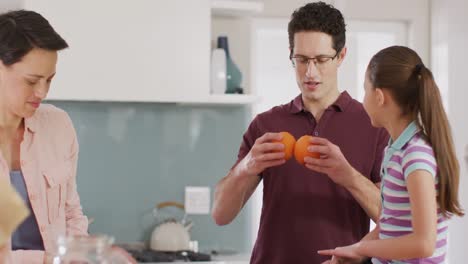 una feliz familia caucásica jugando con la comida en la cocina.