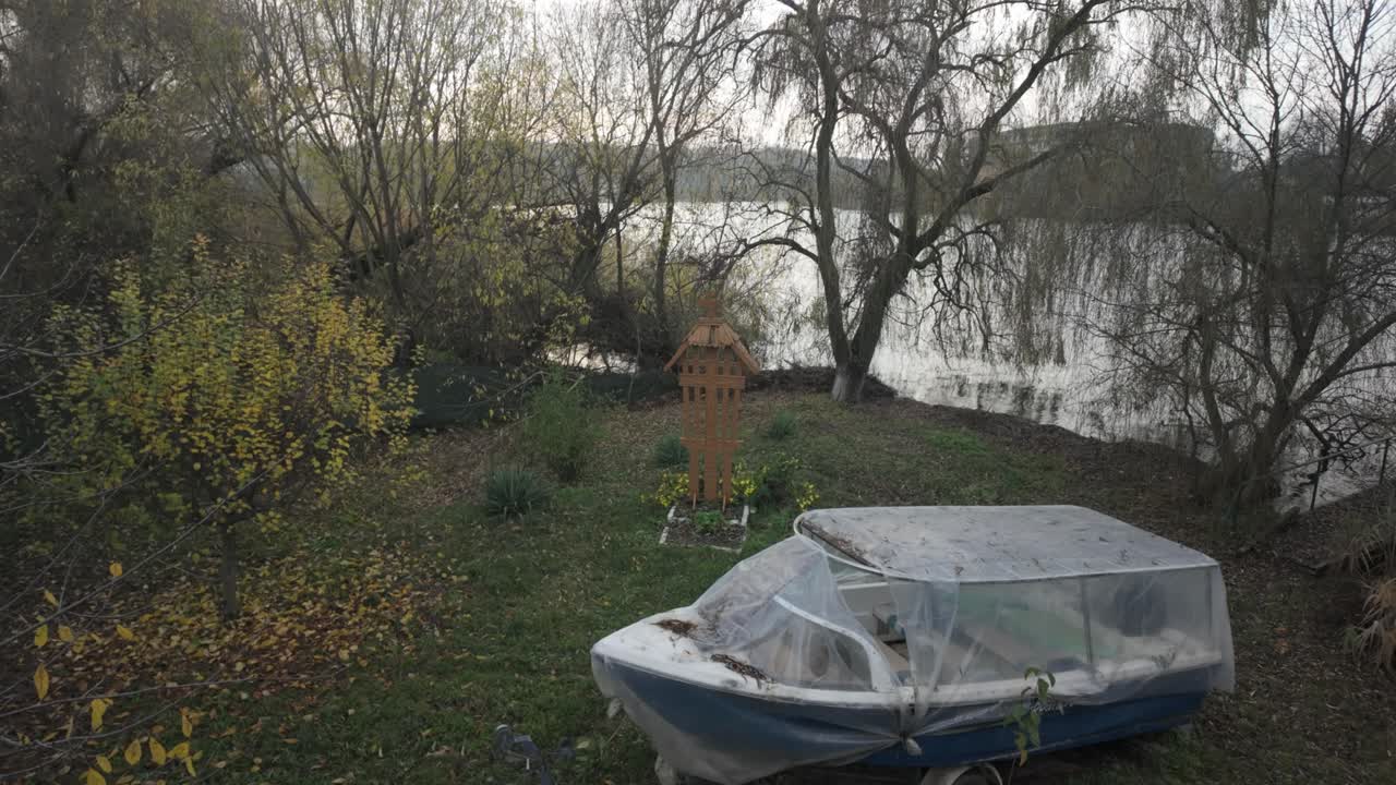 abandoned boat and carved troiță resting on an overgrown Lake Snagov shore