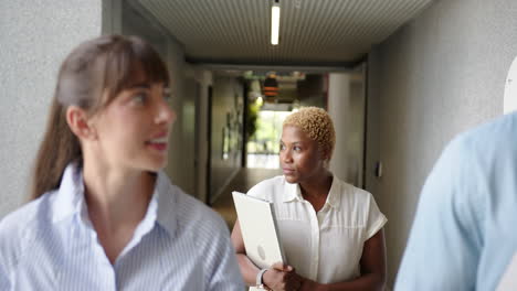 walking in office, diverse businesswomen holding laptop and discussing work
