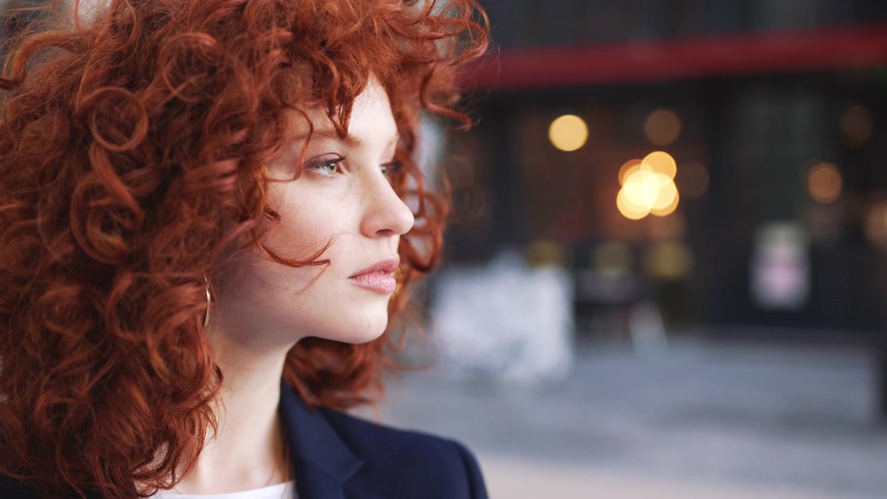 Portrait of a Young Woman with Curly Red Hair Outdoors