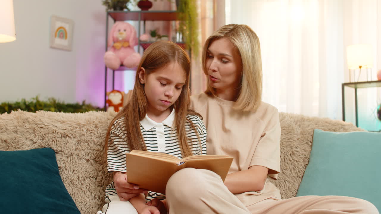 Child girl kid with mom at home listening to bedtime story reacting emotionally on living room sofa