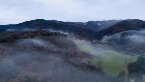 mist clouds over hilly countryside landscape below gray sky, timelapse