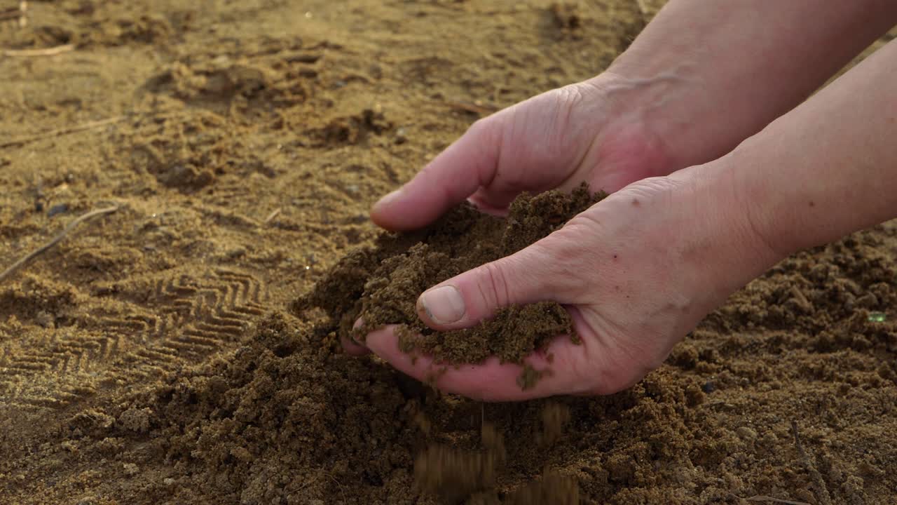 Hands holding golden sand at beach close up shot
