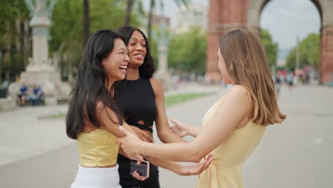 three overjoyed multiracial female friends embracing and feeling excited to meet outdoors