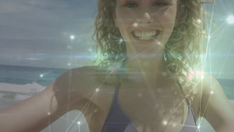 Glowing-network-of-connections-against-portrait-of-caucasian-woman-blowing-a-kiss-at-the-beach