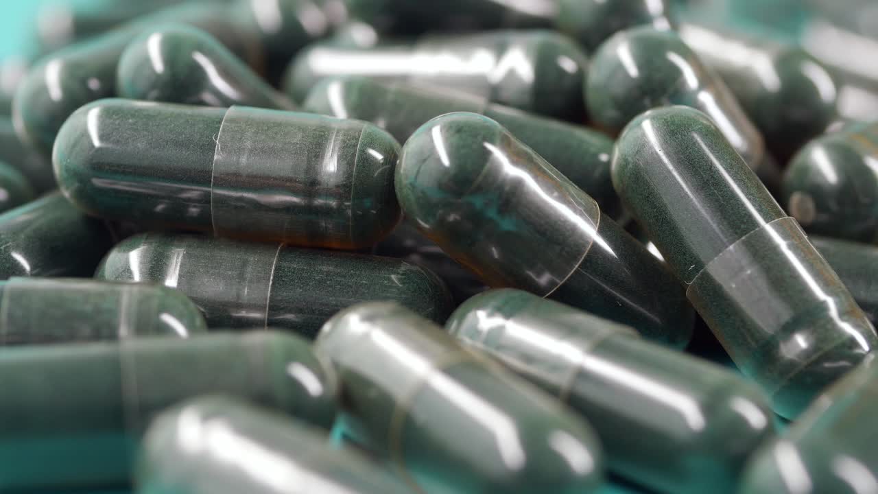 Primo piano di capsule verdi e trasparenti che ruotano su una superficie