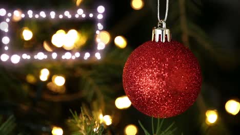 Dekorative-Leuchtende-Lichter-Vor-Der-Nahaufnahme-Einer-Roten-Kugel,-Die-Am-Weihnachtsbaum-Hängt