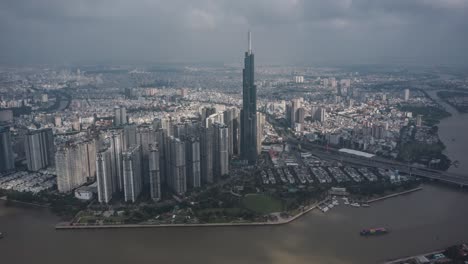 Ho-Chi-Minh-Stadt-Hyperlapse-Luftaufnahme-Eines-Wahrzeichengebäudes,-Des-Saigon-Flusses,-Eines-Dramatischen-Tageshimmels-Und-Des-Bootsverkehrs-Auf-Dem-Wasser