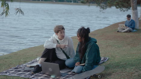 girls sitting with laptop in the park and talking