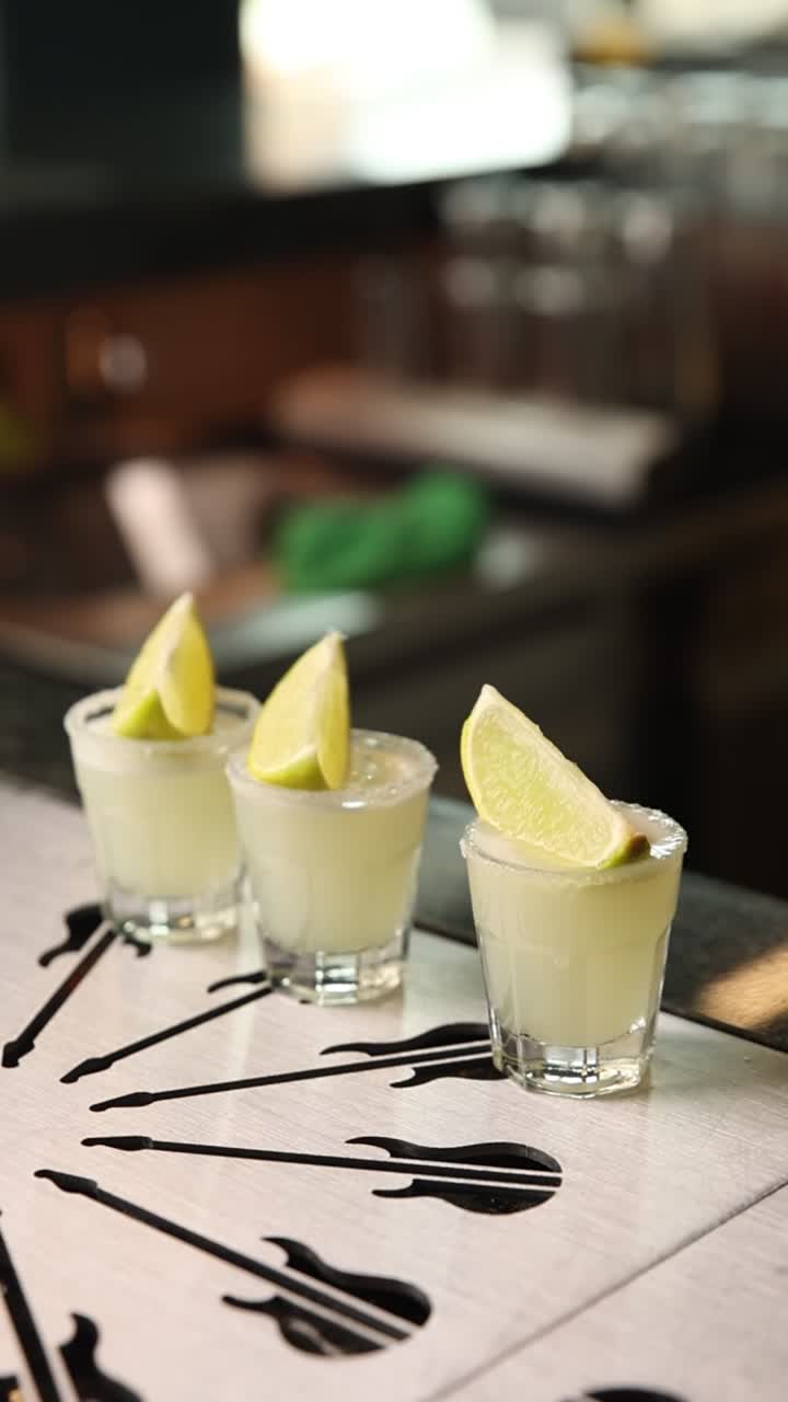 Tre shot di tequila con spicchi di lime e bordi salati su un bancone da bar
