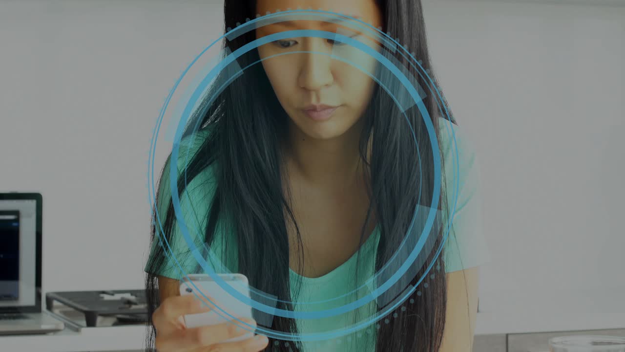 Woman raising phone in kitchen, tapping screen to review cyber security HUD circling head and torso