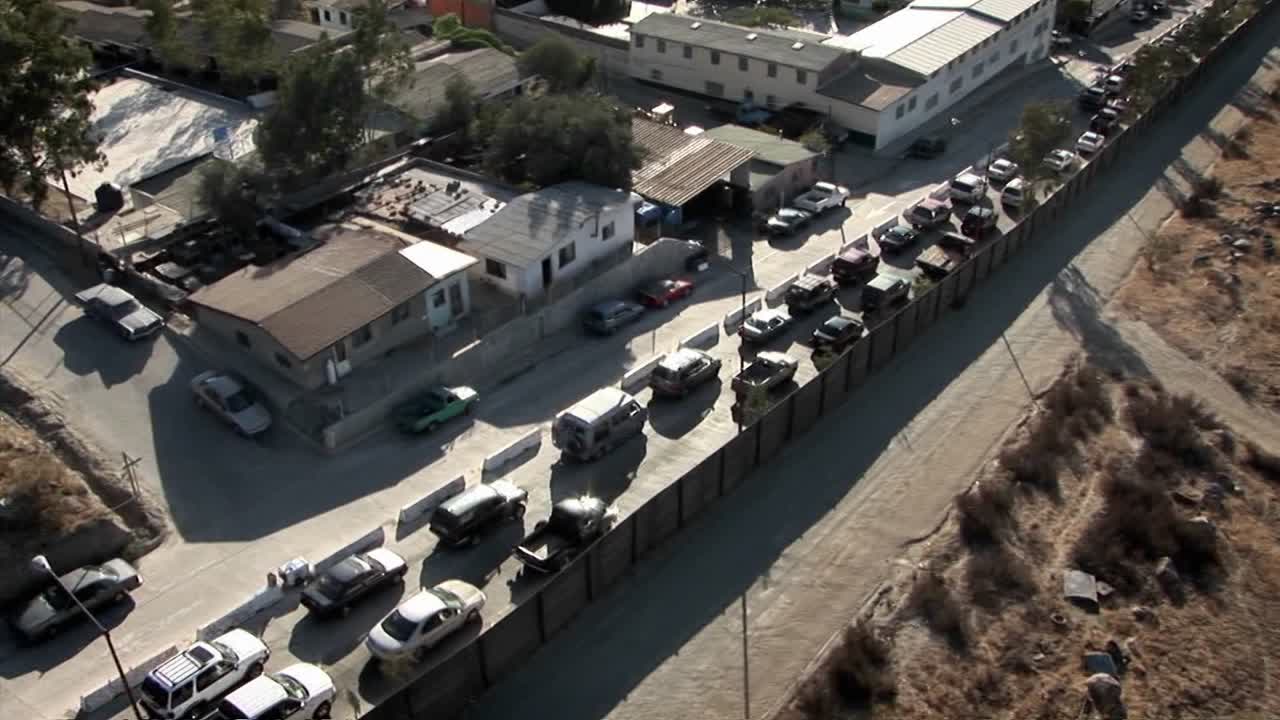 Una fila di auto è in coda per svoltare e altre auto circolano in un quartiere.