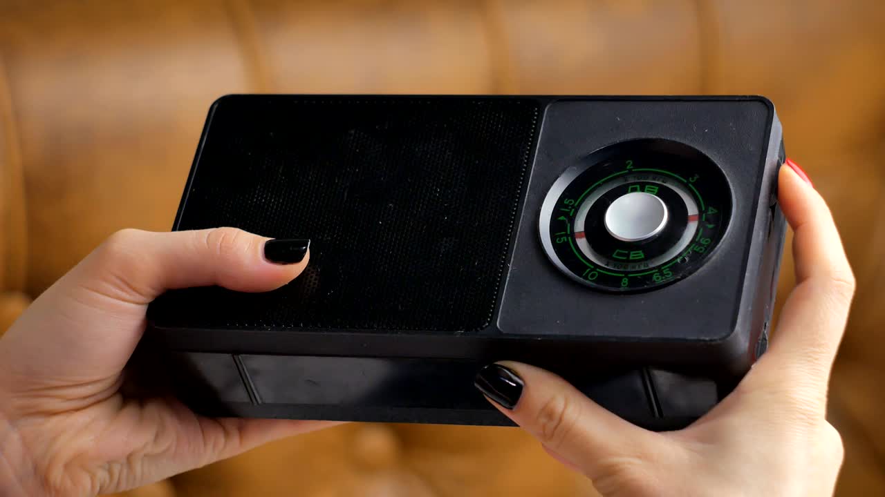 mujeres sintonizando con la mano una radio antigua. la chica está tocando el sonido de la vieja radio.