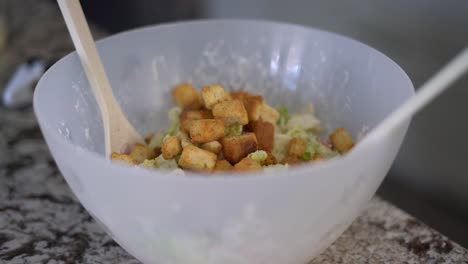 Hinzufügen-Von-Knusprigen-Croutons-Zu-Einer-Großen-Schüssel-Caesar-Salat,-Nahaufnahme-Selektiver-Fokus