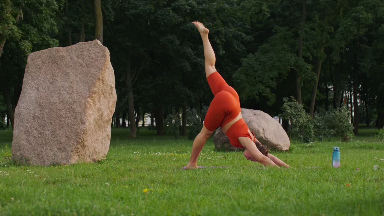 Frau praktiziert Yoga im Freien in einem Park mit Steinen