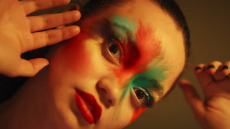 retrato de cerca colorido mujer atractiva con pintura facial fluorescente arte corporal multicolor exótico con luz ultravioleta parpadeante concepto de maquillaje extremo