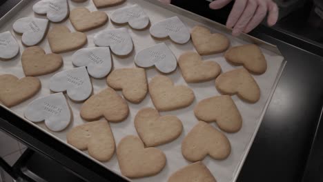 slow motion shot of a woman putting an icing sheet onto freshly baked butter cookies in an artisan pastry shop, 4k