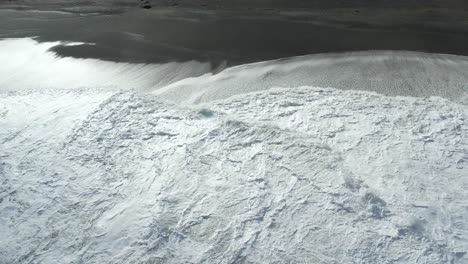 Primer-Plano-Aéreo-De-Agua-Blanca-En-El-Océano-Turbulento-En-La-Playa-Plana-De-Pájaros