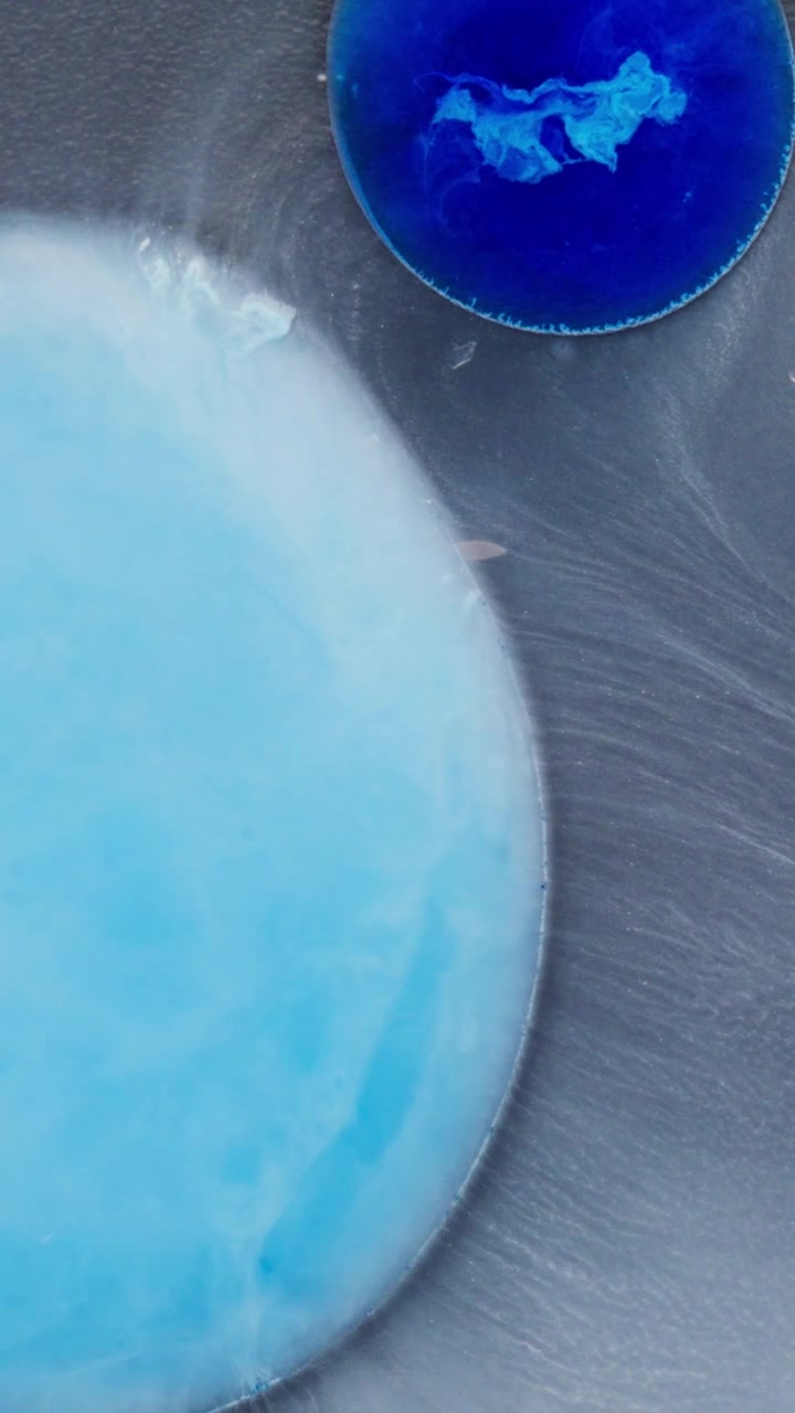 Inchiostro blu che si diffonde e forma spirali nel liquido, creando morbidi motivi organici su sfondo bianco