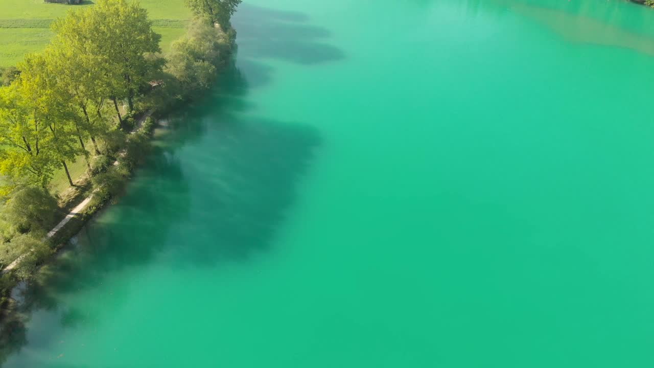 Drone view of turquoise Soča River deep water and green fields, summer day