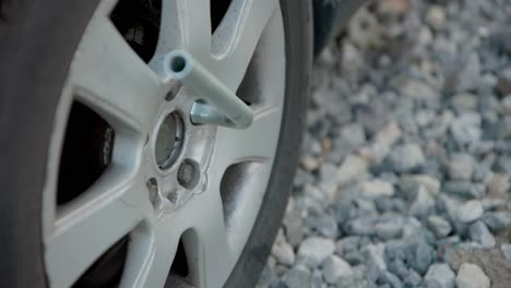 white person places lug wrench to remove nut on flat tire, person steps on tool