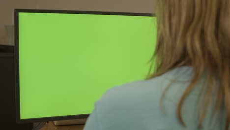 dolly of woman sitting behing a green computer screen