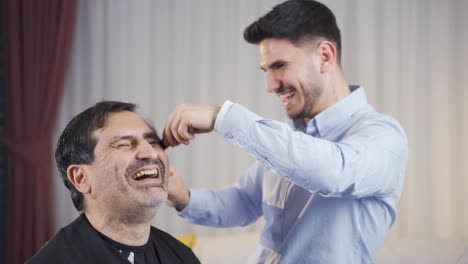 el joven afeita el cabello de su padre en casa.