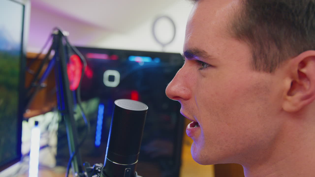 여러 모니터와 함께 책상에 앉아서 집에서 게임을 하는 남자