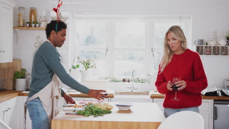 Pareja-Vistiendo-Disfraces-De-Astas-Haciendo-Un-Brindis-Mientras-Prepara-La-Cena-El-Día-De-Navidad