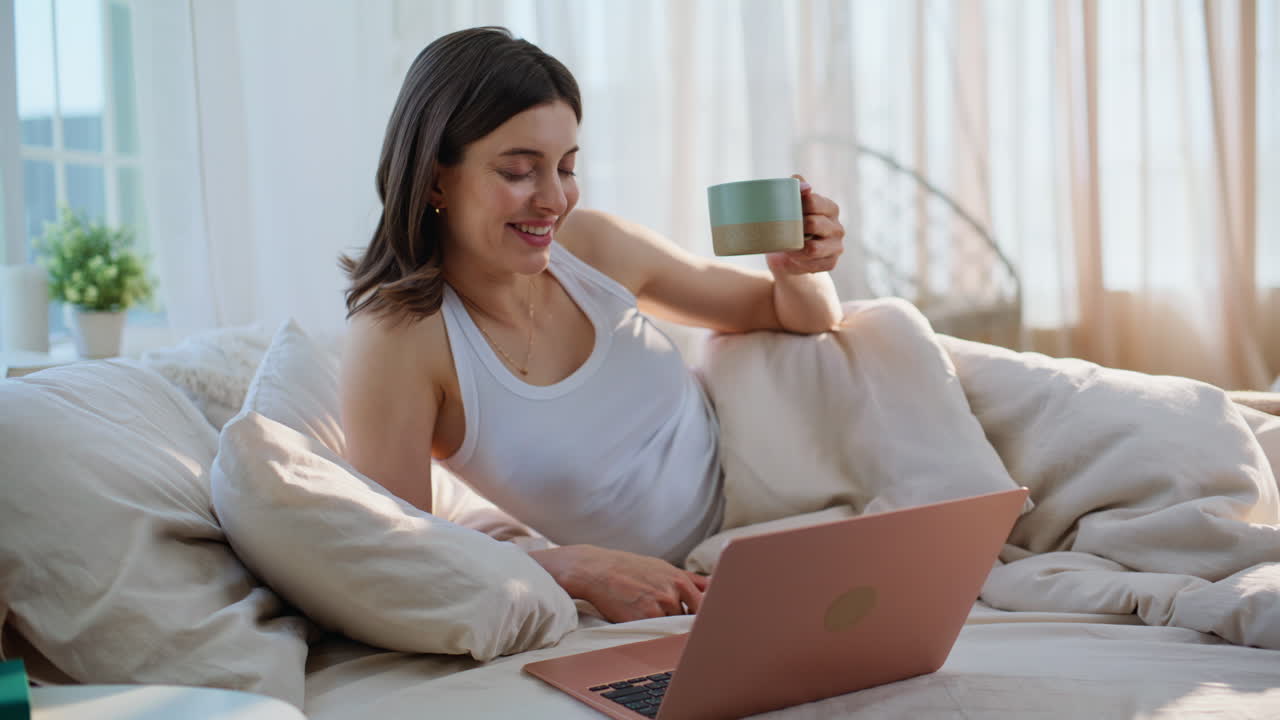Mulher fazendo uma chamada de vídeo na cama e tendo uma conversa amigável remota pela manhã, close-up
