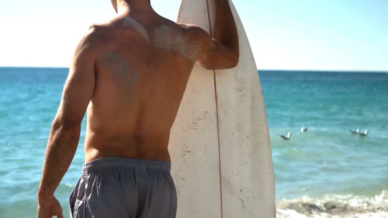 hombre sosteniendo una tabla de surf en la playa
