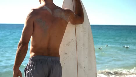 Hombre-Sujetando-Tabla-De-Surf-En-La-Playa