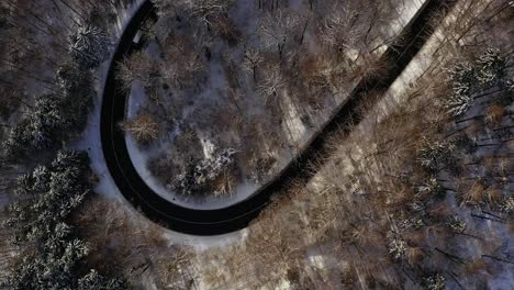 topdown aerial winter view at a driving car, follow up a winding street by a look up shot and the 4k clips ends with the beautiful view at the bavarian monastery schäftlarn sourrounded by white snow