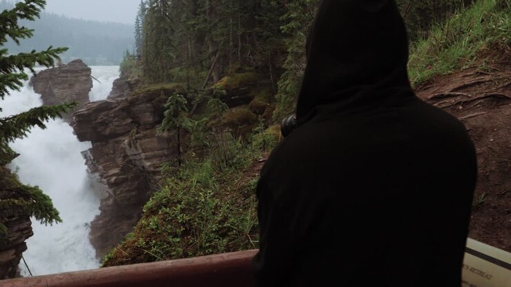 Man taking pictures from a lookout at Athabasca Water Falls in Jasper National Park, Alberta, Canada