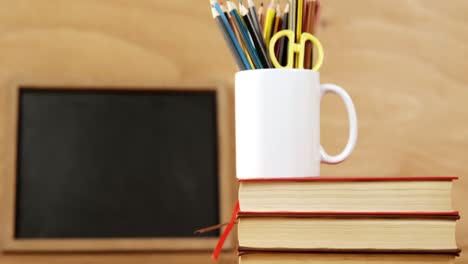 libros apilados con lápices de color en una taza