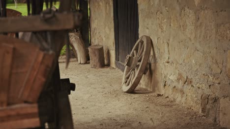 old wooden wheel leaning against stone wall