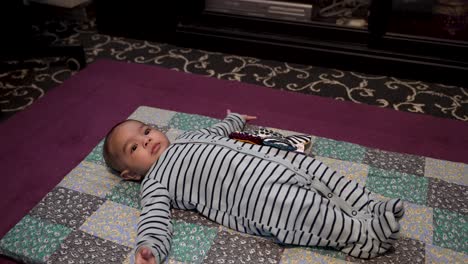 Adorable-Bebé-Indio-De-4-Meses-Tirado-En-Una-Alfombra-En-El-Suelo,-Retorciéndose-Y-Gesticulando