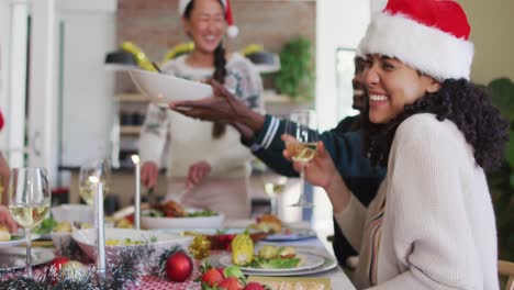 happy mixed race woman in santa hat celebrating meal with friends at christmas time