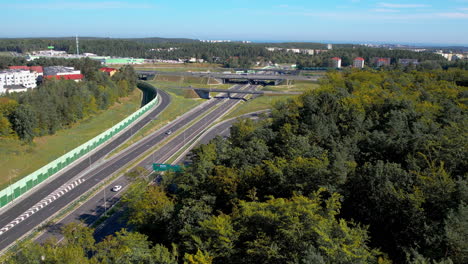 aerial - flight over the expressway and road intersection - the road close to the forest and greenery - modern design of expressways