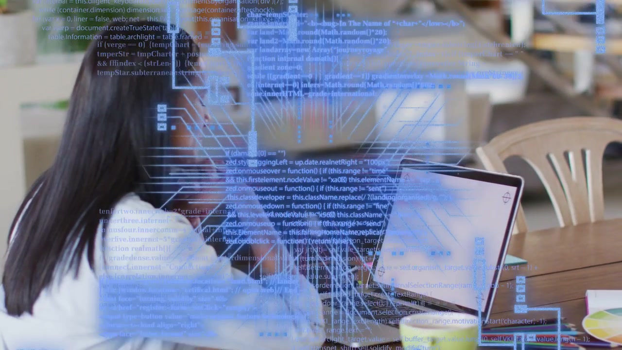 Donna che lavora nel settore tecnologico a un tavolo, con lo schermo del laptop illuminato che proietta codice animato sul tavolo.