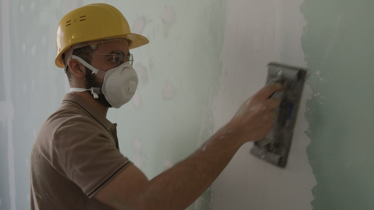 Construction worker sanding a wall